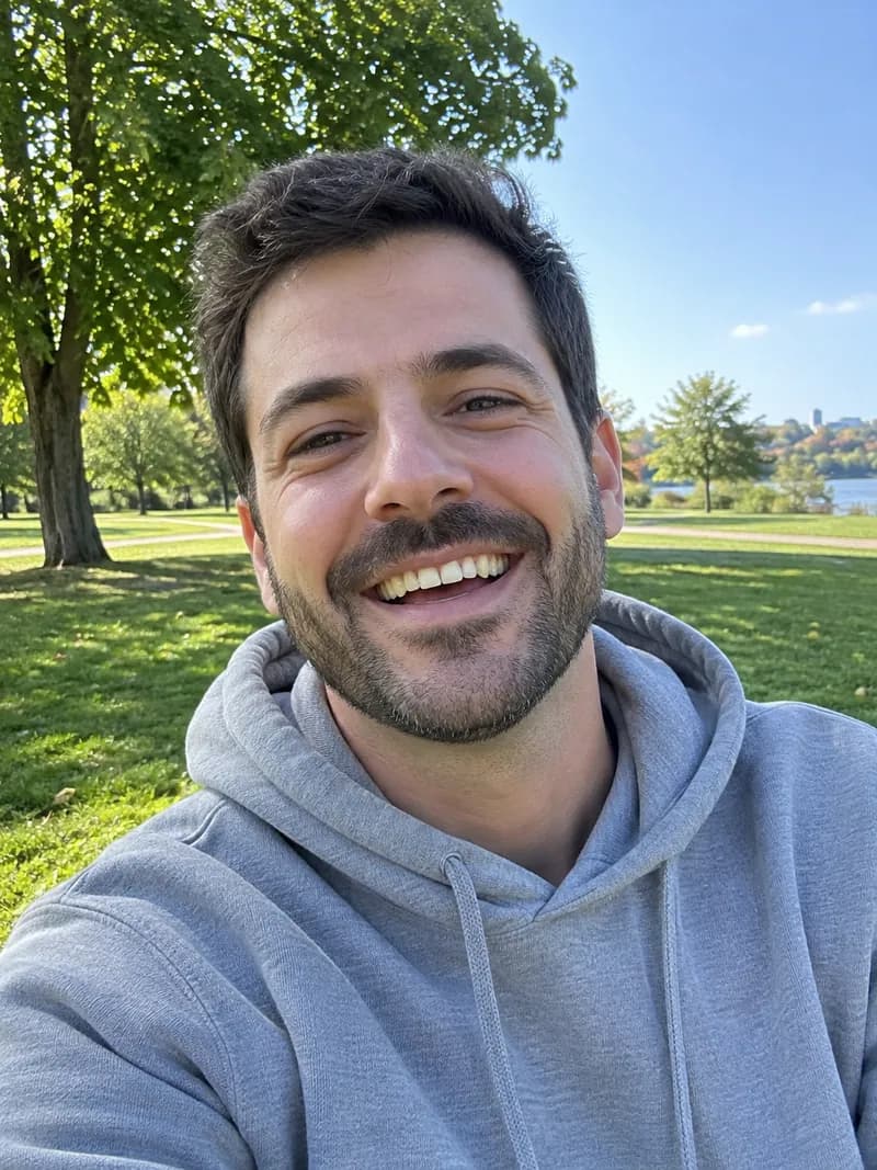 Original photo: a bearded man in a grey hoodie laughing in a sunny park
