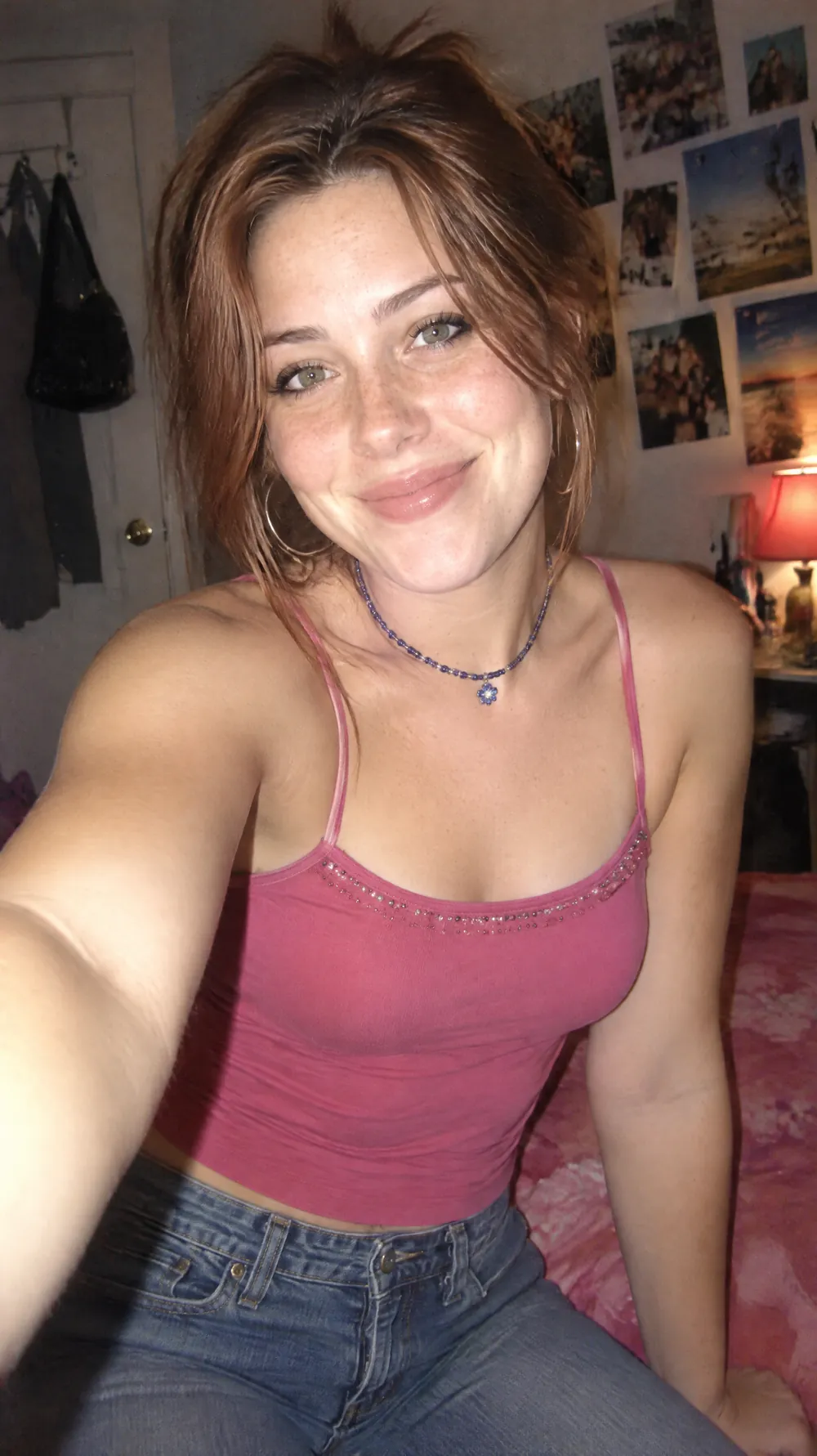 Y2K digital camera selfie of a woman in a pink tank top in a bedroom, with harsh flash and soft focus