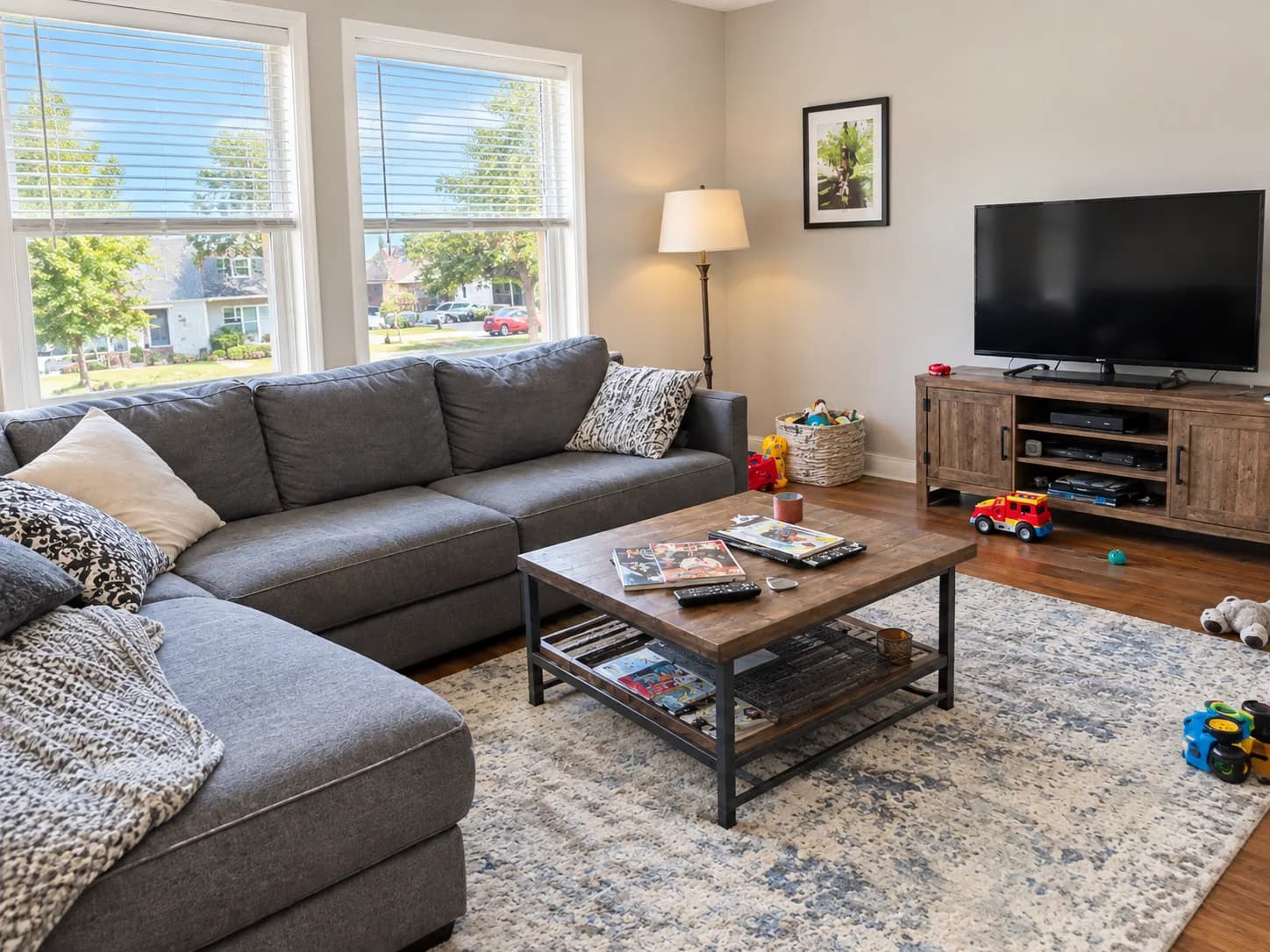 Living room with a gray sectional sofa after enhancement: brighter light and toys cleared from the floor