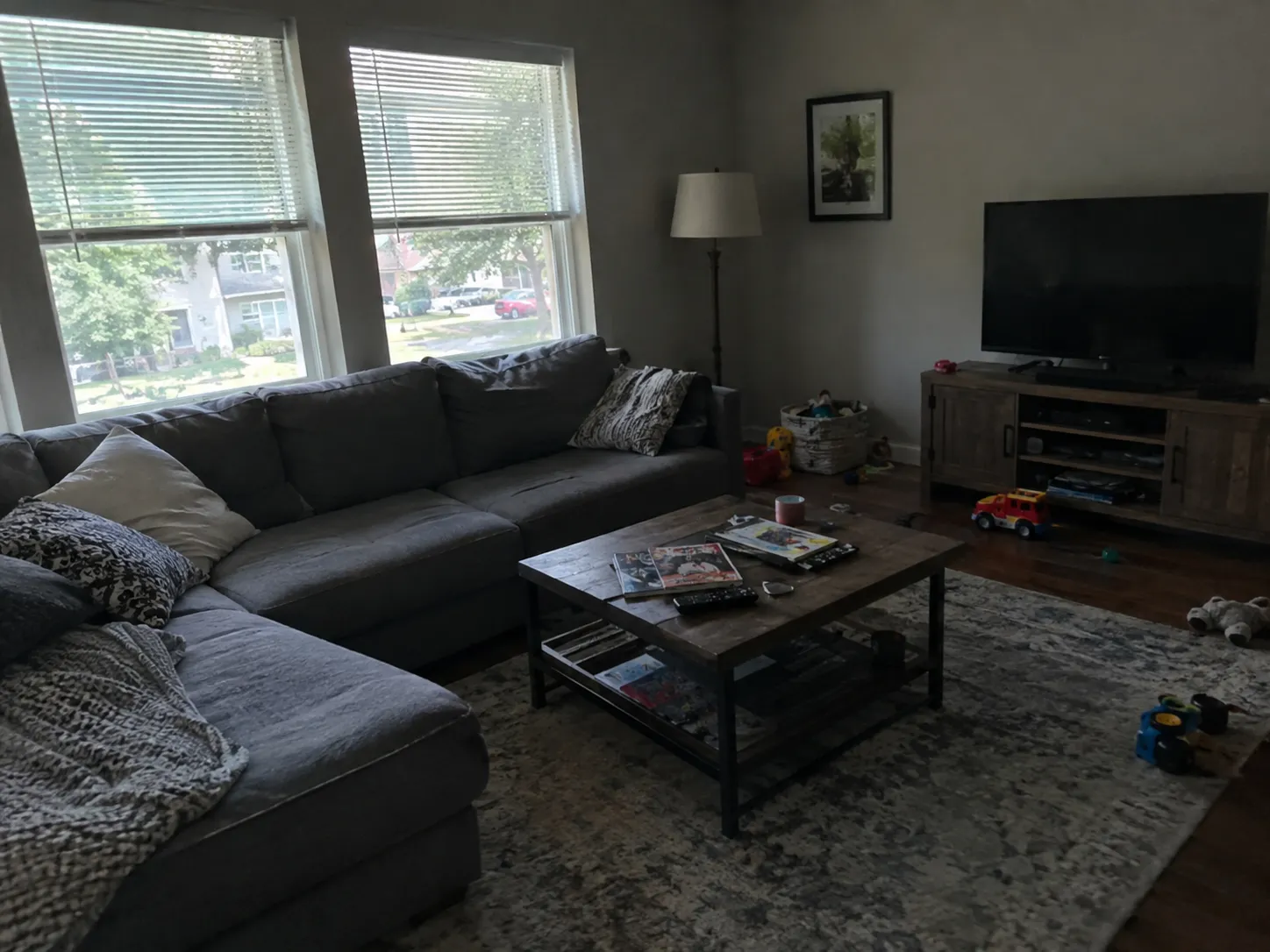 Original living room photo: darker lighting, toys on the floor and a cluttered coffee table