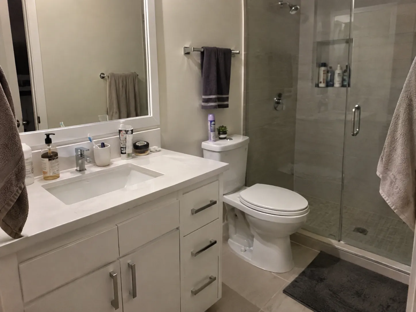 Original bathroom photo with toiletries on the vanity and a towel in the foreground